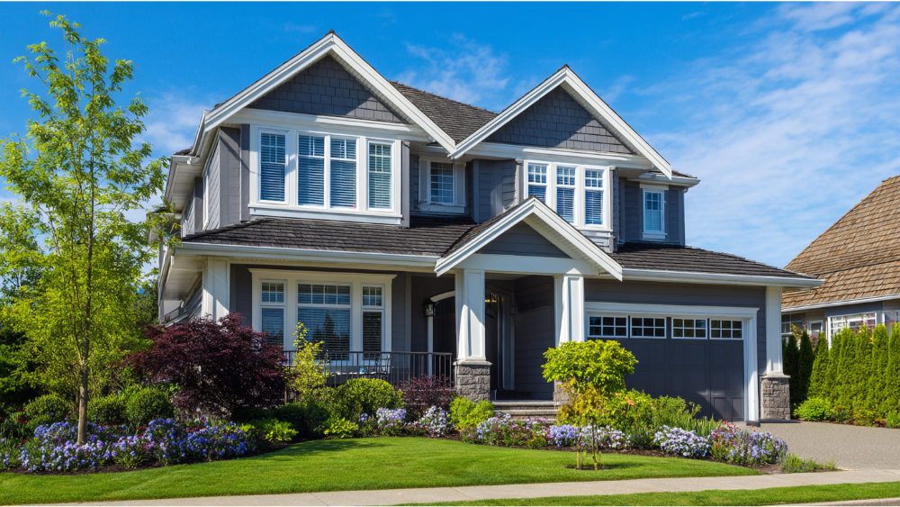 Gray vinyl-sided home with white trim and lush landscaped front yard