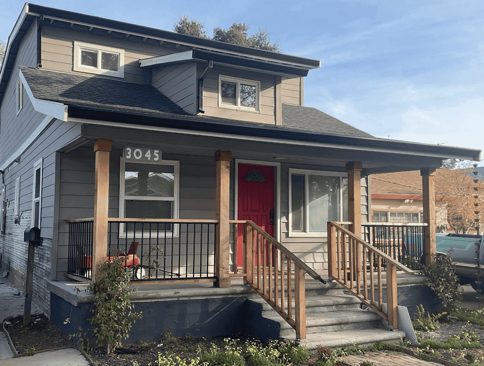house with gray siding and red front door with a porch